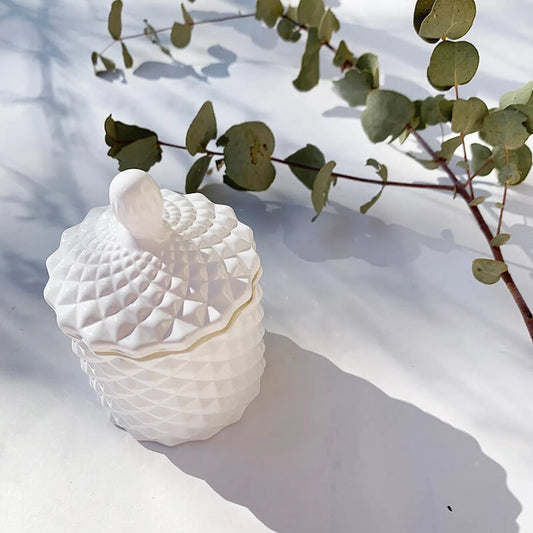 Closed-lid geometric jar luxury coconut candle infused with lavender essential oil, set against a background of eucalyptus leaves for a natural and elegant ambiance.