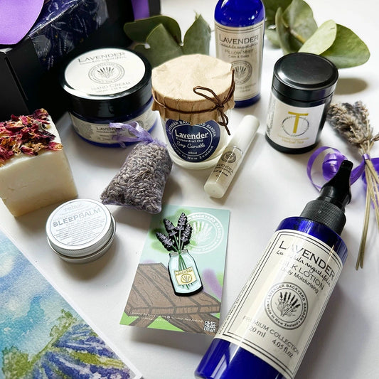 Close-up view of luxury lavender pampering gift set for women, featuring a Lavender Essential Oil Soy Candle, Sleep Balm, Lip Balm, Essential Oil Soap, Pillow Mist, Silk Lotion, Chamomile & Lavender Loose Leaf Tea, Hand Cream, Lavender Fridge Magnets, Mini Lavender Dry Flower, and a Lavender Field Bookmark — perfect for relaxation and self-care.