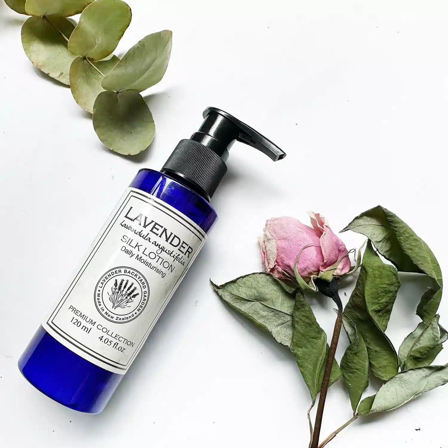 Moisturizing lavender body lotion with dried eucalyptus and dried rose as background decor.